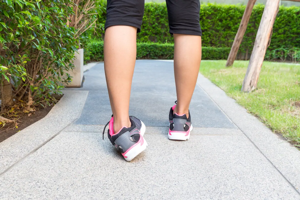 Legs of a person walking along a garden path