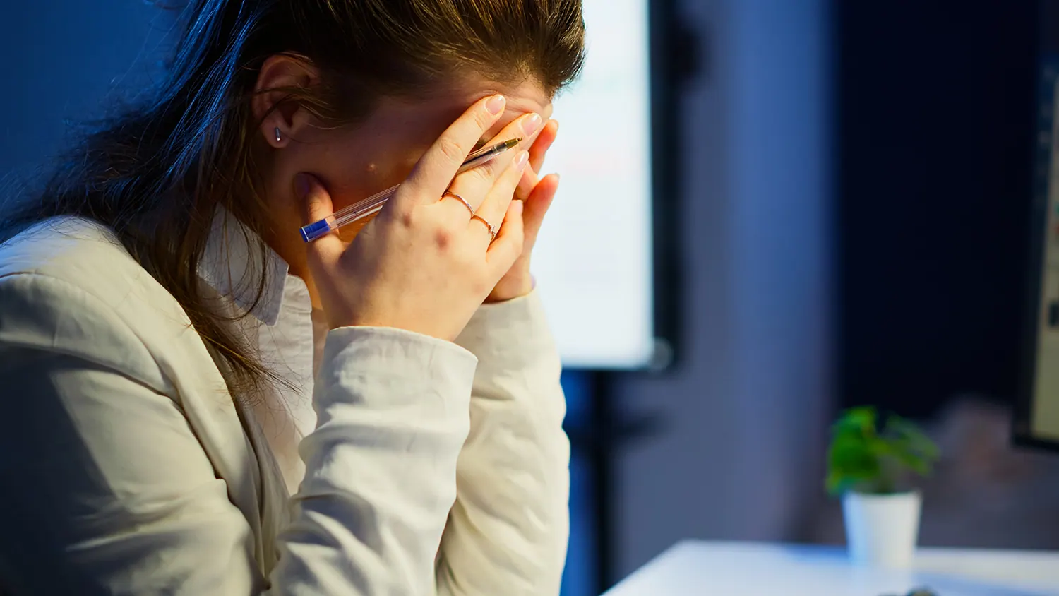Woman at a desk covering her face with her hands