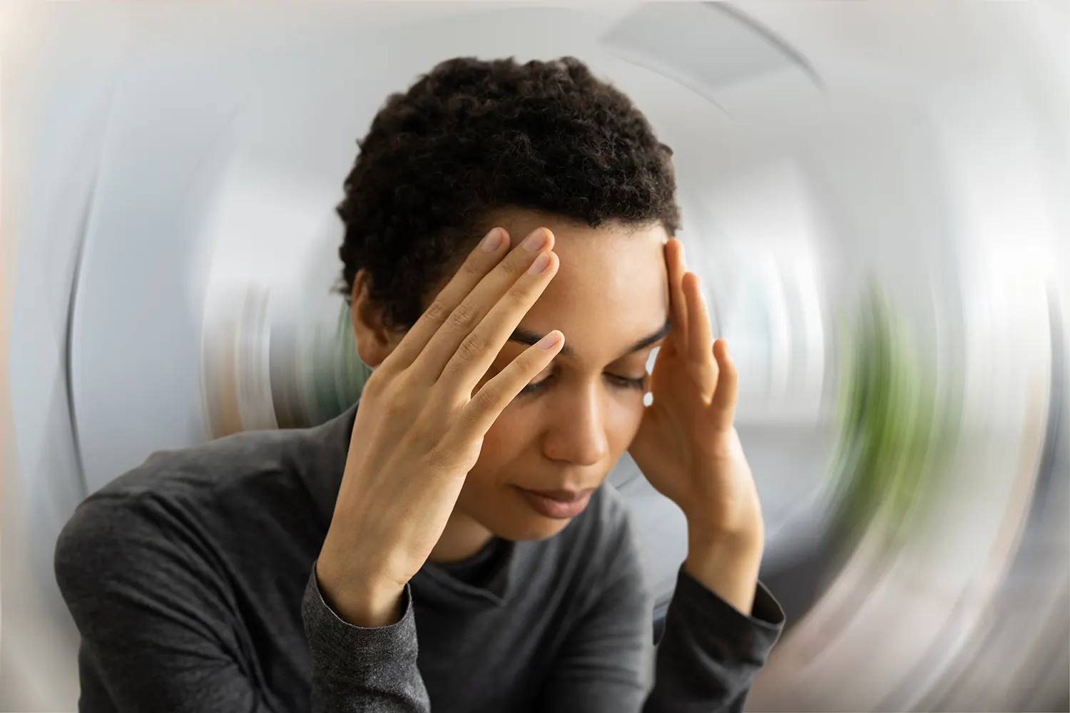 Woman holding her head against a spinning, blurred background