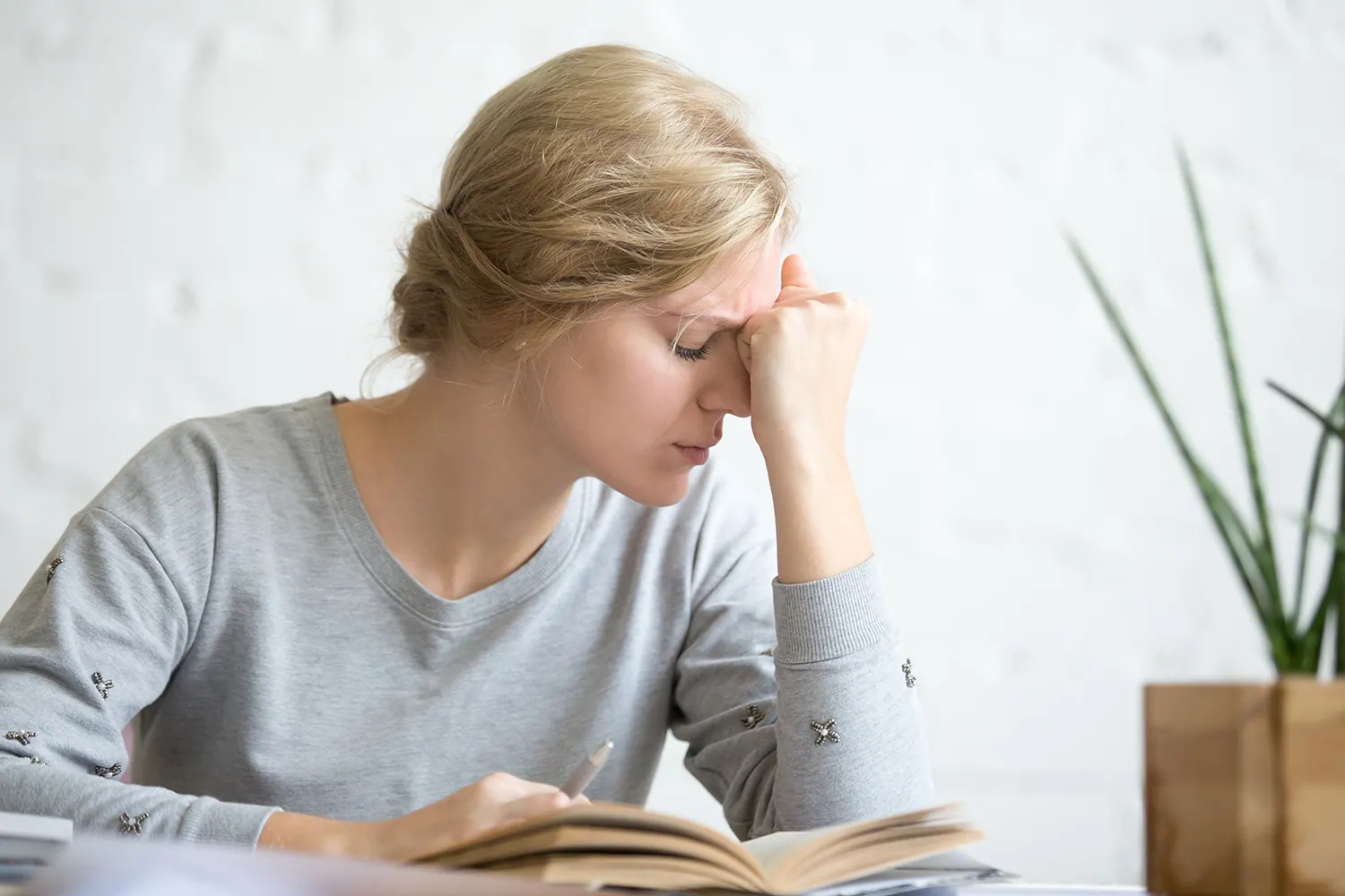 blond woman taking a nap due to vertigo pain while reading a book